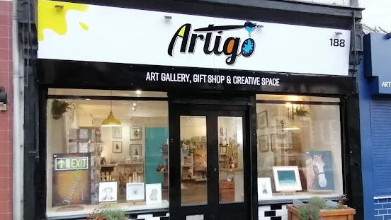 Artiglo art gallery, gift shop, and creative space storefront with glass windows and black and white facade.